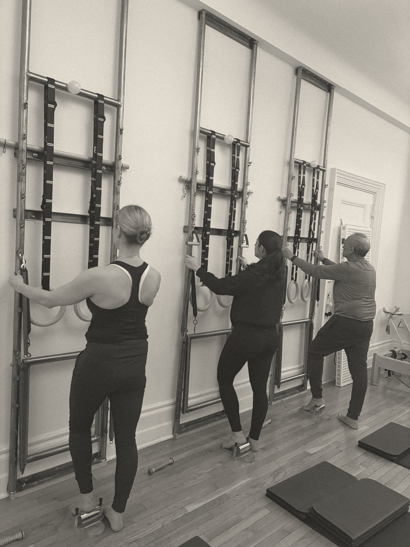 Three clients standing at the wall units in a semi-private Pilates class at Will Taylor Studio